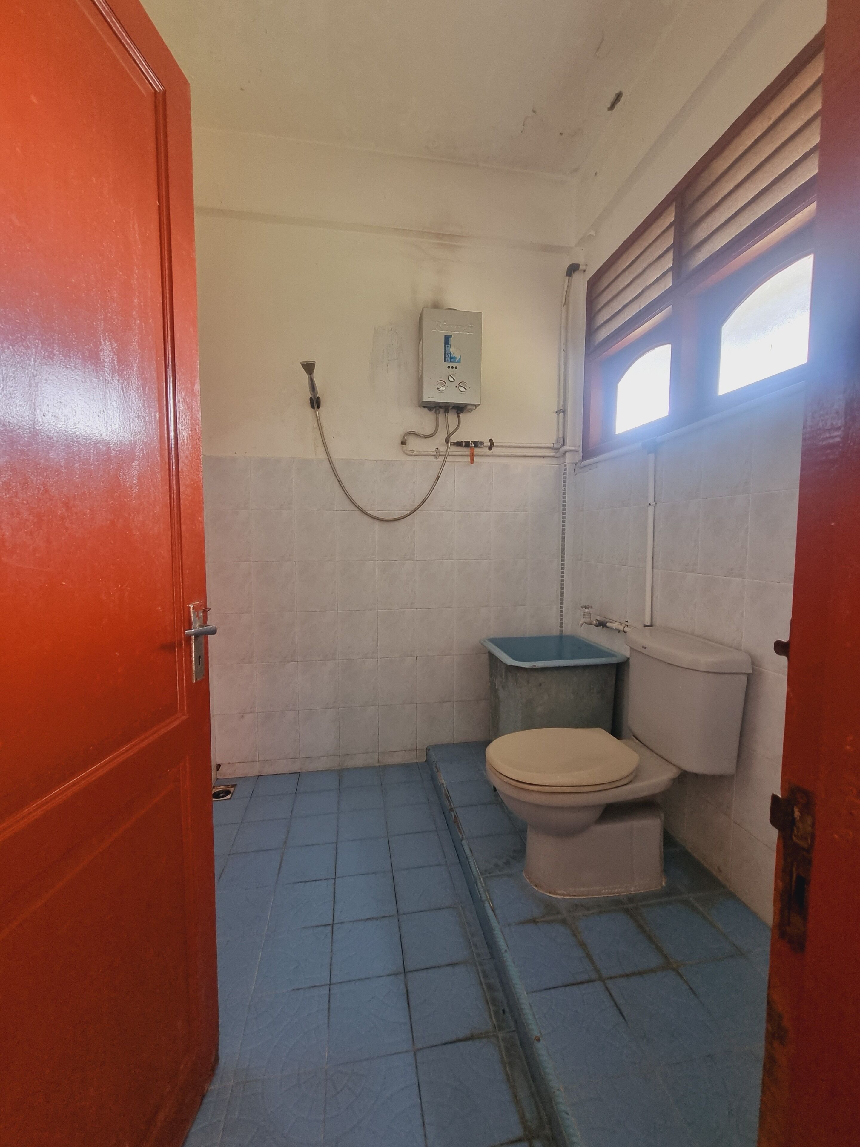 A small, compact bathroom with a toilet, a shower, and a sink.