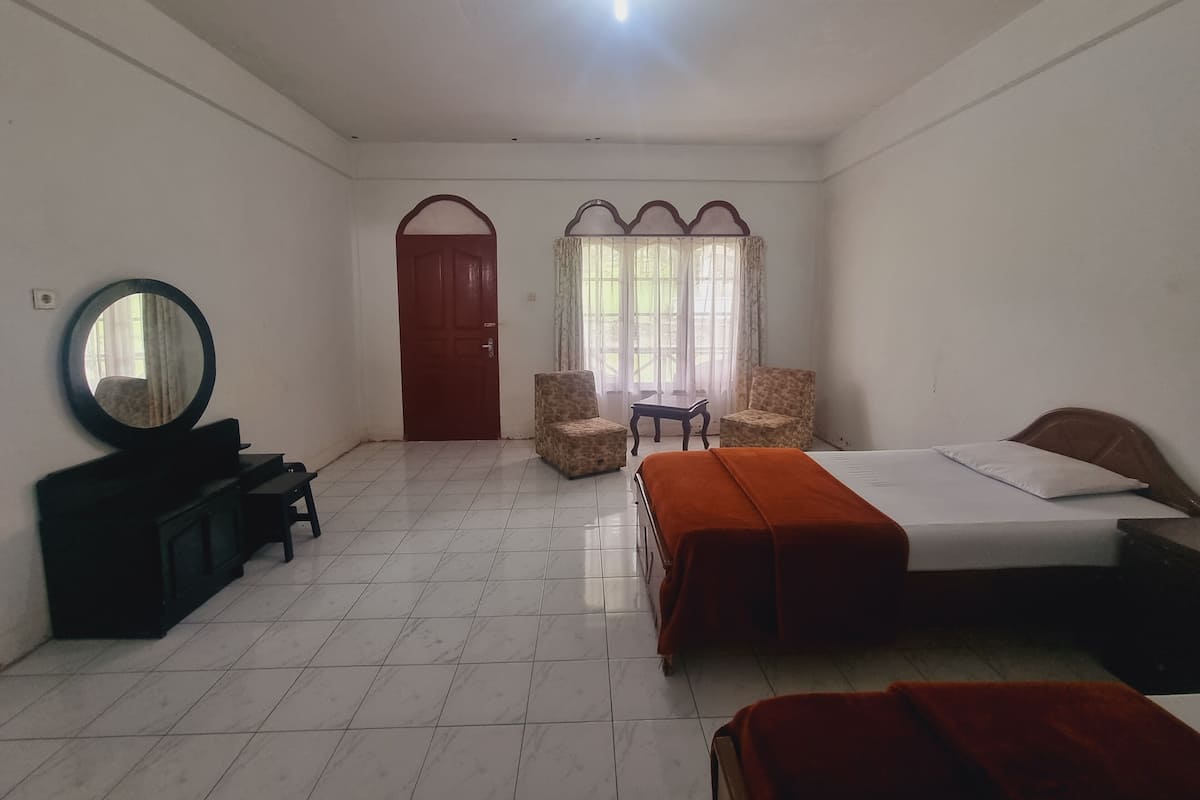 Um quarto com cama, cadeira, mesa, espelho e porta.