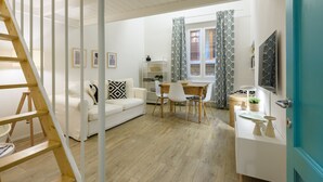 A modern living room with a white sofa, wooden dining table, and a staircase. - Madame Betta by Mmega (Florence)