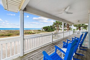 A covered porch with blue chairs and a view of the beach. - Sunny Moon: 4 Bedroom Gulf Beaches Home- Sleeps 10, Pet Friendly, Private Pool! (St. George Island)