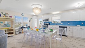 Una cocina moderna con armarios blancos, una mesa de comedor de vidrio y sillas de plástico transparente.