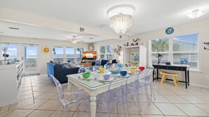 Una cocina amplia con una mesa de vidrio, sillas transparentes y un candelabro.