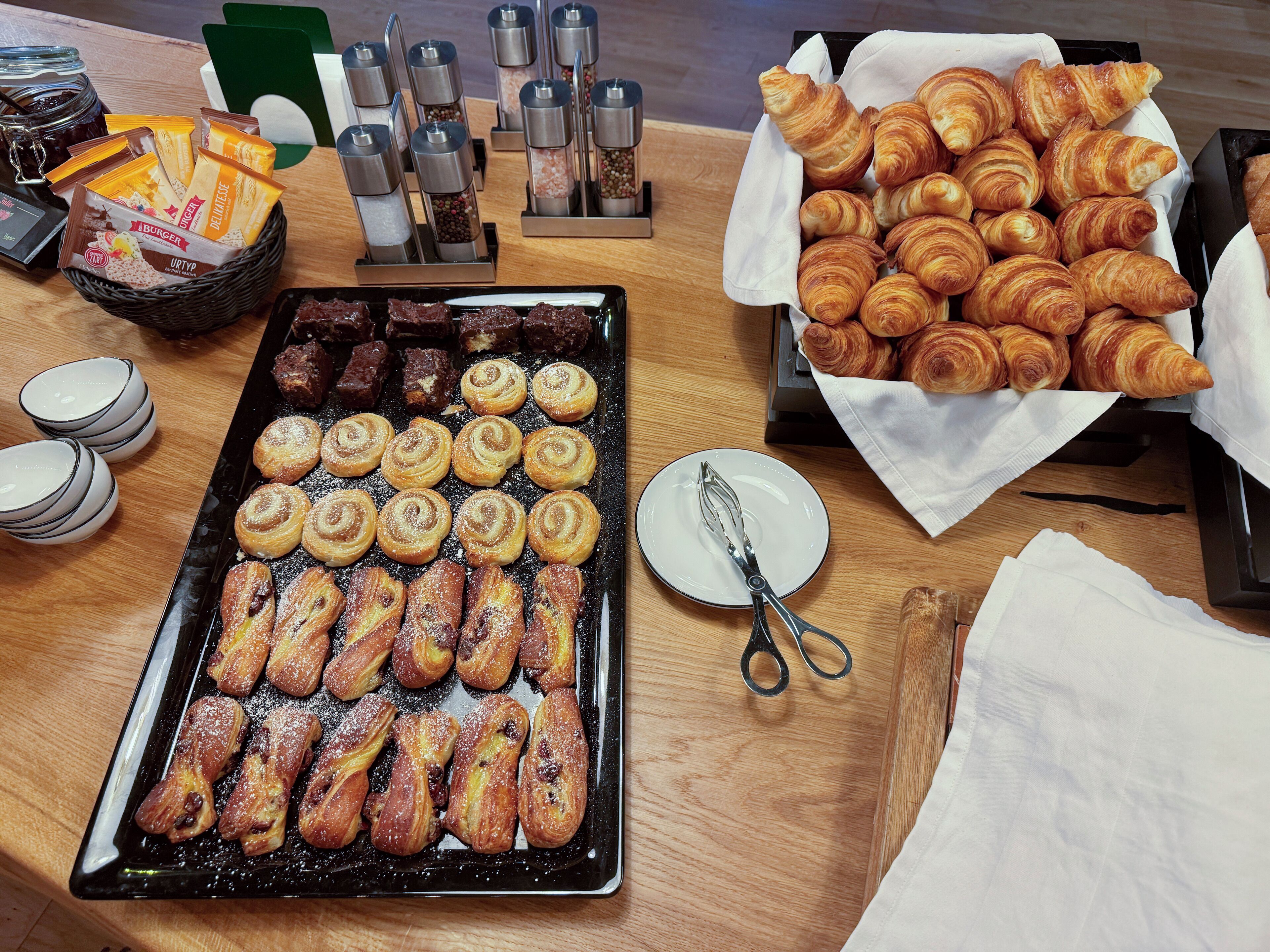 Una mesa de buffet con pasteles, condimentos y utensilios.