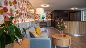Uma sala de estar moderna com sofá, mesa de centro redonda e painéis decorativos na parede.