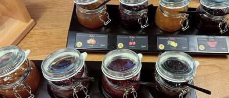 Verschiedene Gläser Marmelade mit Etiketten, die Geschmacksrichtungen wie Aprikose, Himbeere und Pflaumensauce angeben.
