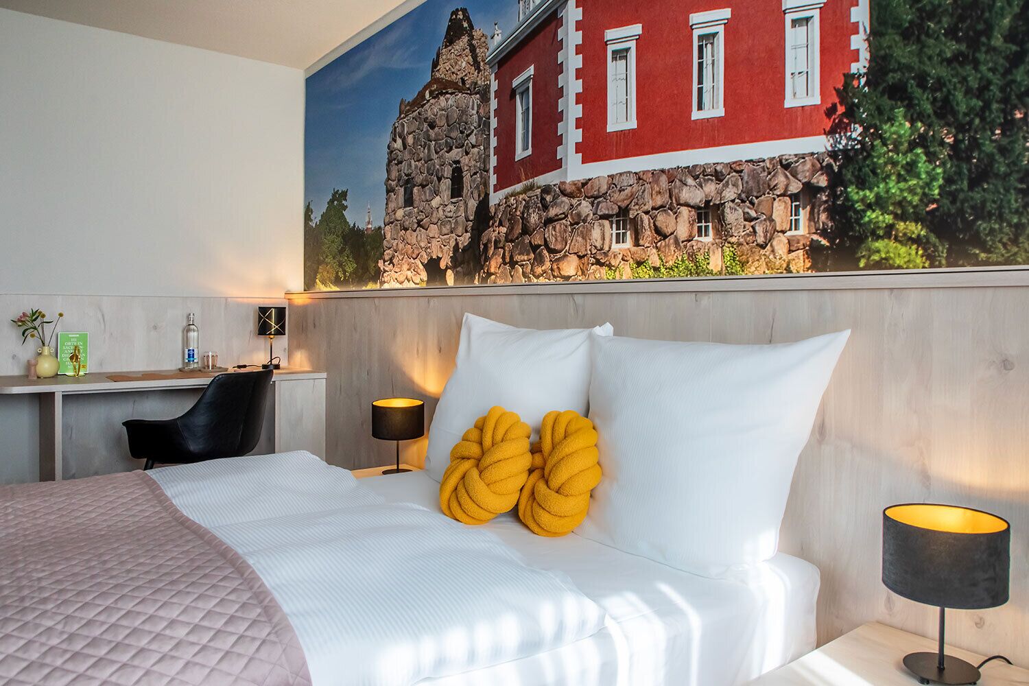 Een hotelkamer met een bed, een bureau, een stoel en een lamp.