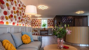 Uma sala de estar moderna com um sofá, uma mesa redonda de madeira e um vaso com flores.
