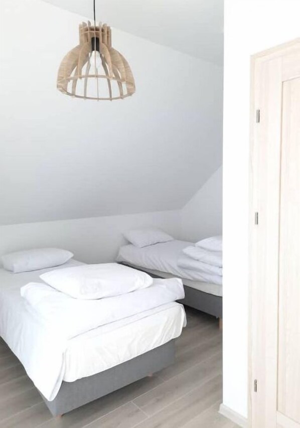 Un dormitorio con dos camas, una lámpara colgante y un armario de madera.