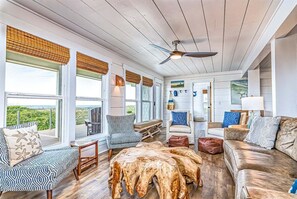 A spacious living room with a large wooden coffee table, a ceiling fan, and a view of the outdoors.