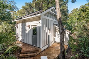 Surrounded by lush greenery, this cozy cabin features a front door and a small porch area.
