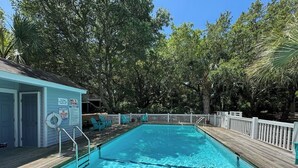 Une piscine rectangulaire avec une terrasse en bois, un poste de surveillance pour les sauveteurs et une clôture blanche qui l’entoure.