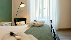 A neatly made bed with rolled towels, a green blanket, and a black headboard.