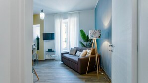 A modern living room with a sofa, a small table, a floor lamp, and a television.