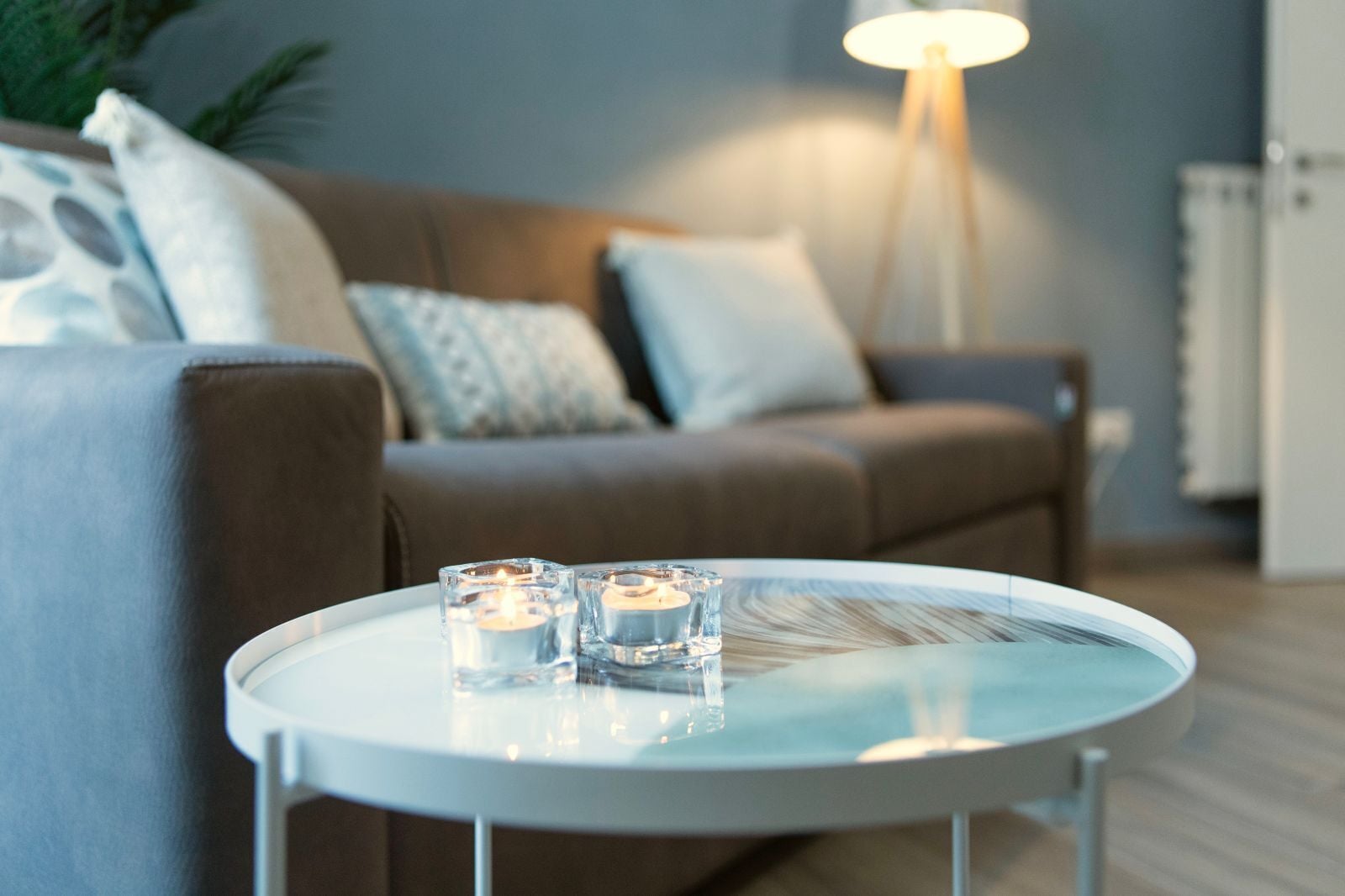 A round white table with two lit candles in clear glass holders.