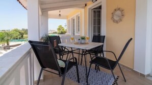 Un área de estar al aire libre techada, con una mesa y sillas, y vistas del paisaje, además de un reloj en la pared.