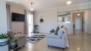 Una sala de estar moderna con un sofá, una mesa de centro y un televisor montado en la pared.