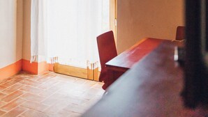 Une pièce avec un plafond en bois, un rideau blanc, une table en bois et des chaises rouges.