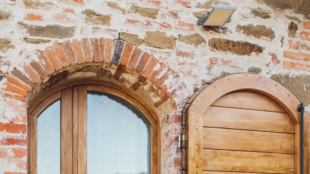 Une porte en bois avec un panneau de verre et un mur en briques.