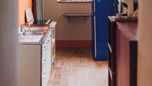 A narrow kitchen with a window, a blue refrigerator, and a wooden ceiling. - Podere Biricocolo-Il Cortile- In the  countryside, 20 km from  Siena.  (Toscana)