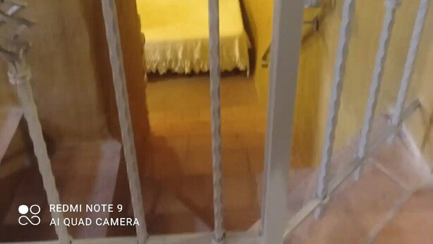 Quarto com cama, cabeceira de madeira e mesa de cabeceira.