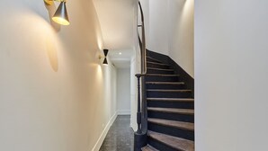 A staircase with a wooden handrail and black steps leading to a landing.