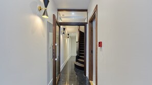 Ein Korridor mit schwarzem Marmorboden, einer Holztreppe und einer Wandleuchte.