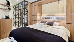 Une chambre moderne avec un grand lit, une tête de lit en bois et des étagères intégrées.