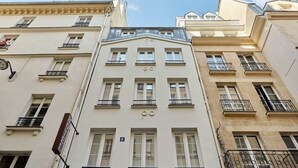 Un immeuble à plusieurs étages doté d’une entrée centrale, de nombreux balcons et d’un style architectural classique.