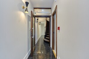 Stylish corridor with a polished floor and staircase leading to an upper level.
