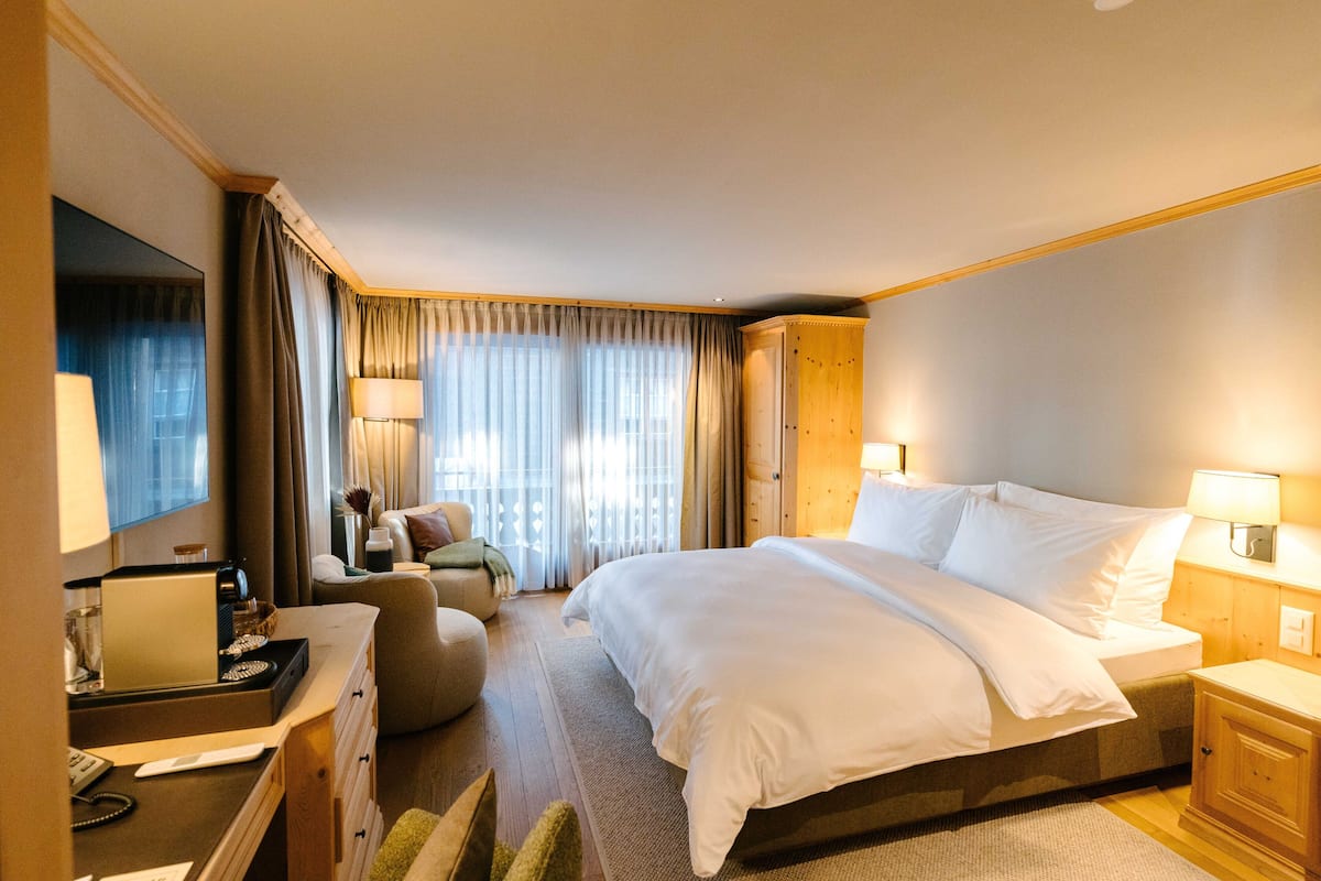 Habitación de hotel con una cama grande, un escritorio con una computadora portátil, una silla y un televisor.
