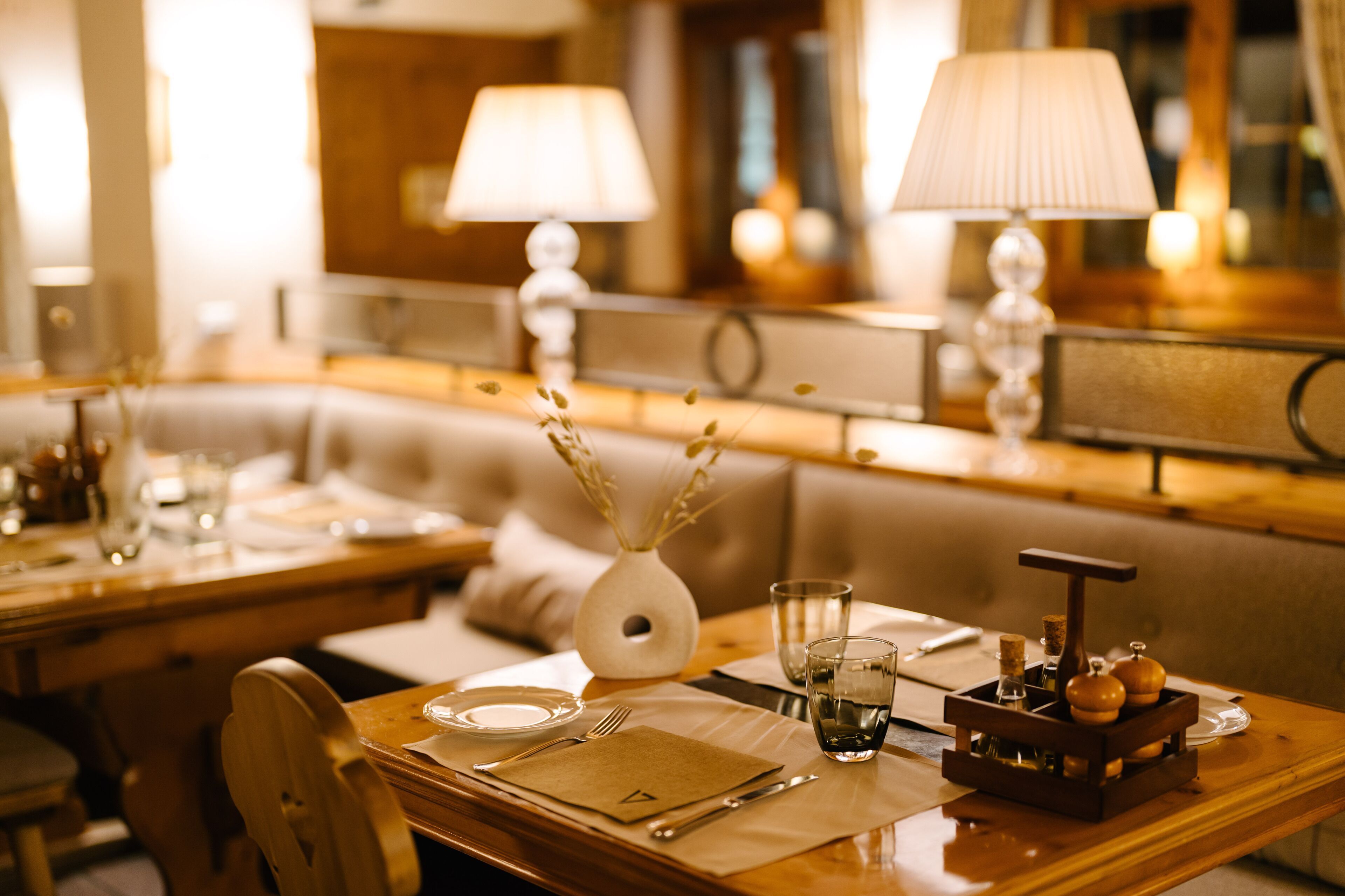 A dining area with wooden tables, white tablecloths, and candles.