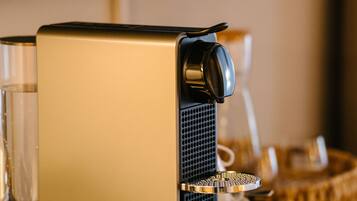 A coffee machine with a tray, glasses, and a basket on a table.