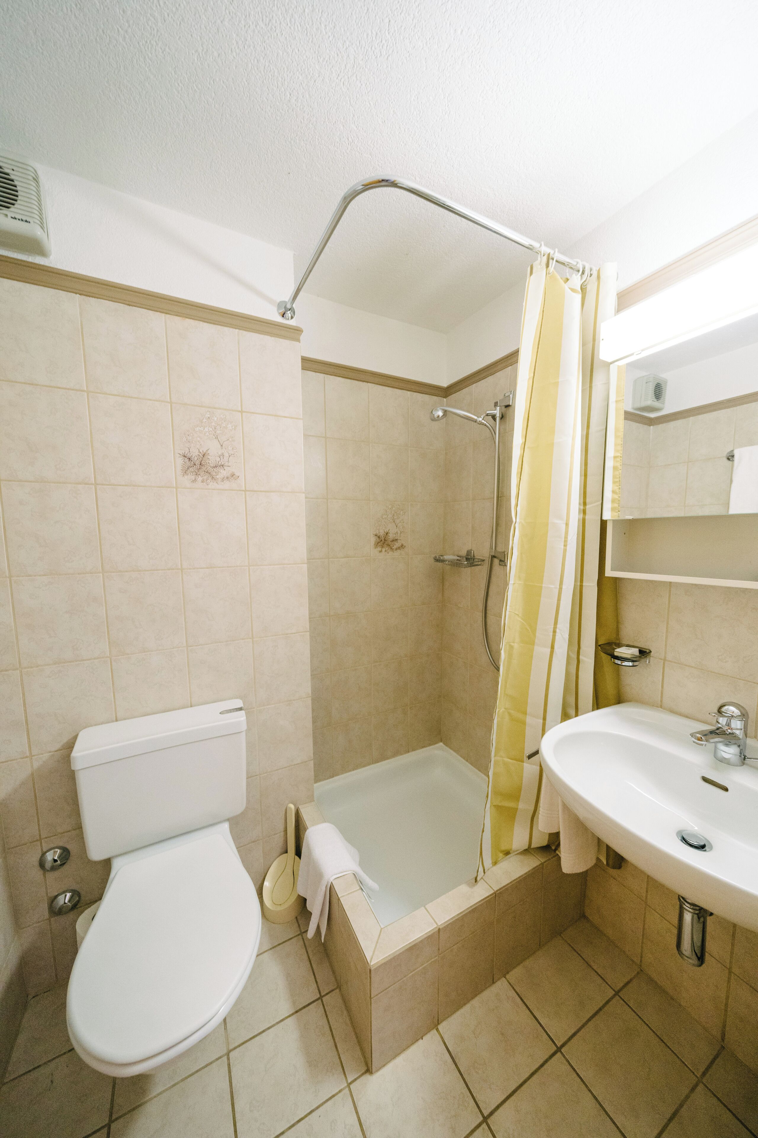 A bathroom with a toilet, shower, and sink.