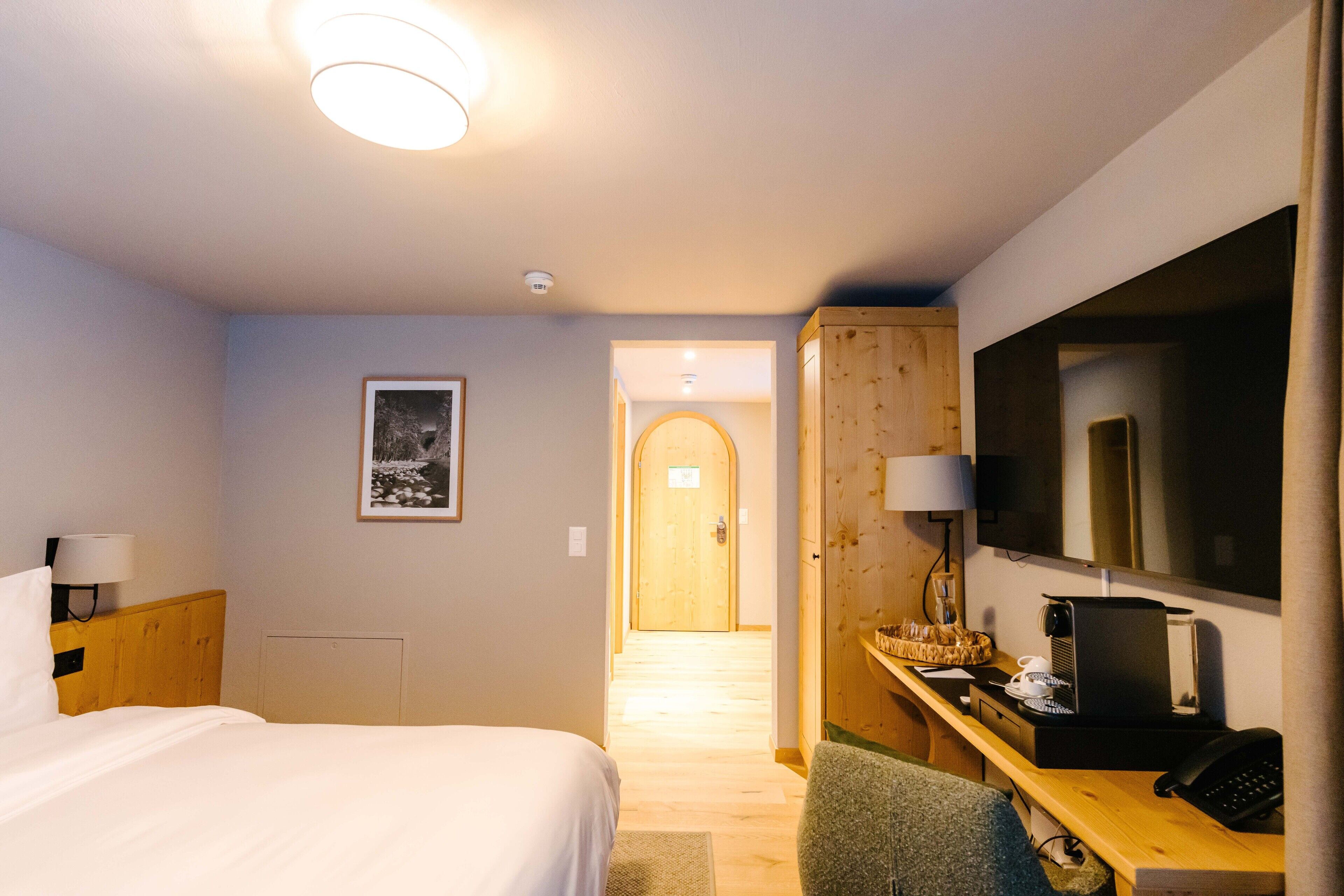 A hotel room with a bed, desk, chair, and a television.