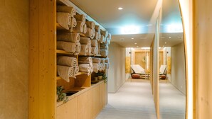 A hallway with wooden shelves holding rolled towels, a reception area, and a seating area with chairs. - Seven Alpina Boutique Hotel (Klosters-Serneus)