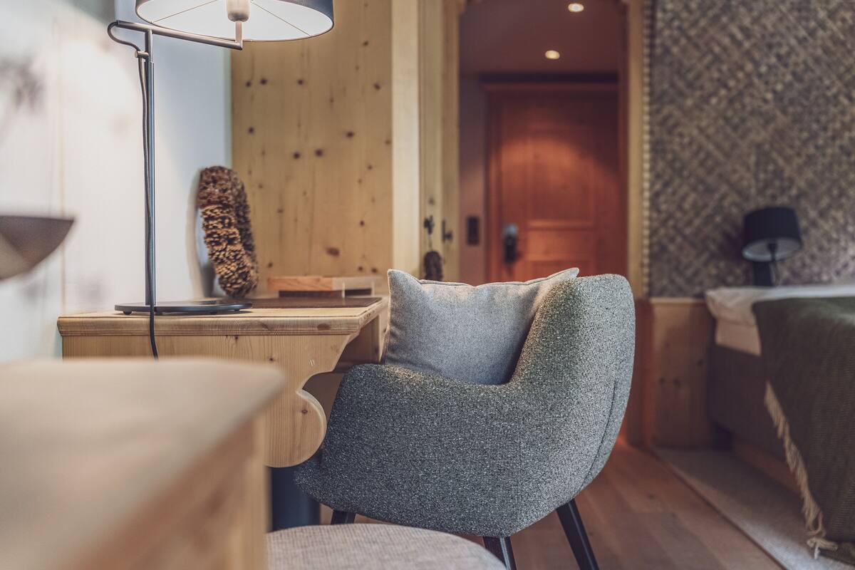 Una habitación acogedora con un escritorio de madera, una silla y una cama.
