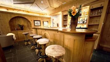A bar area with wooden stools, a bar counter, and a flower vase.