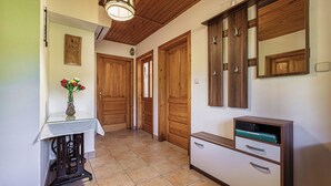 A hallway with wooden doors, a glass table with a vase, and a cabinet with drawers.