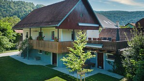 A two-story house with a sloped roof, a balcony, and a small garden area.