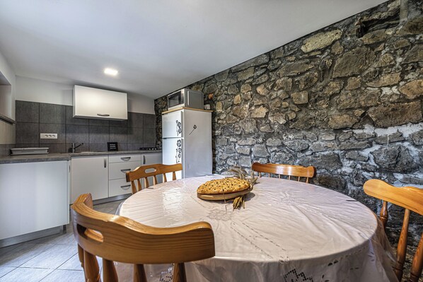 Enjoy family meals at this kitchen, featuring a dining table for four and modern appliances.