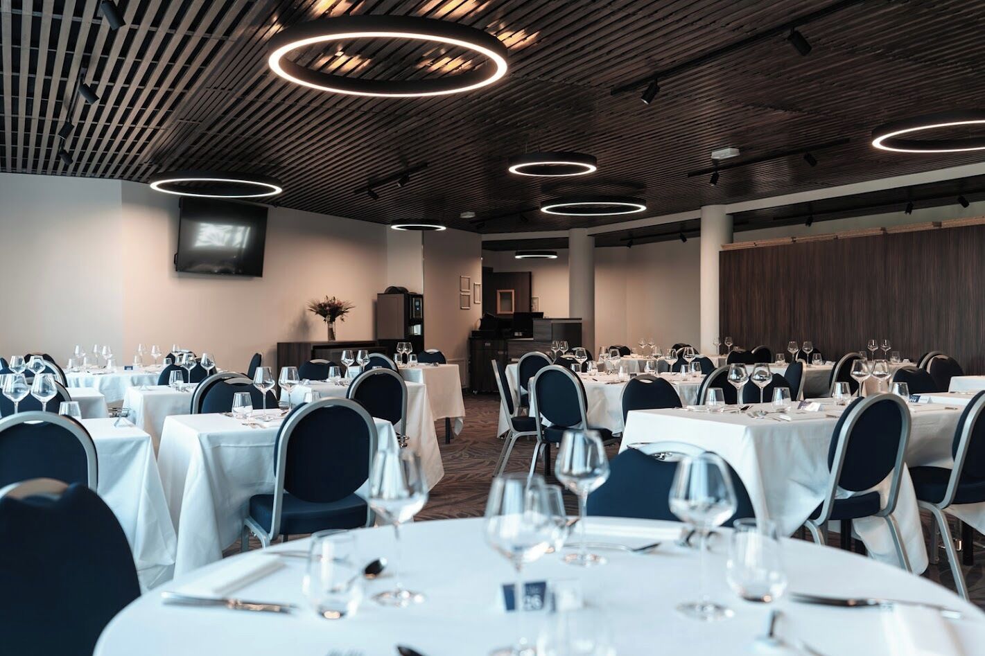 A conference room with round tables, chairs, and a stage.