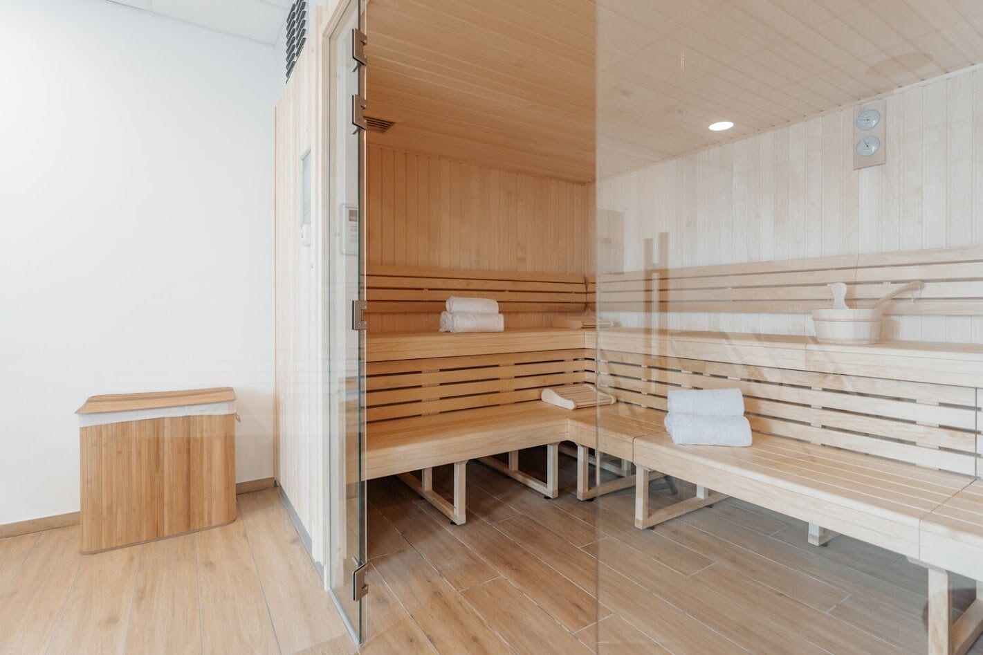 A sauna room with wooden benches and a glass partition.
