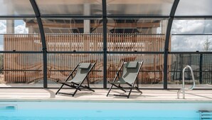 A pool area with two lounge chairs and a metal pool ladder.