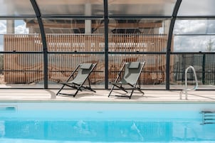 Un área de piscina con dos sillas de descanso y una escalera metálica para la piscina.