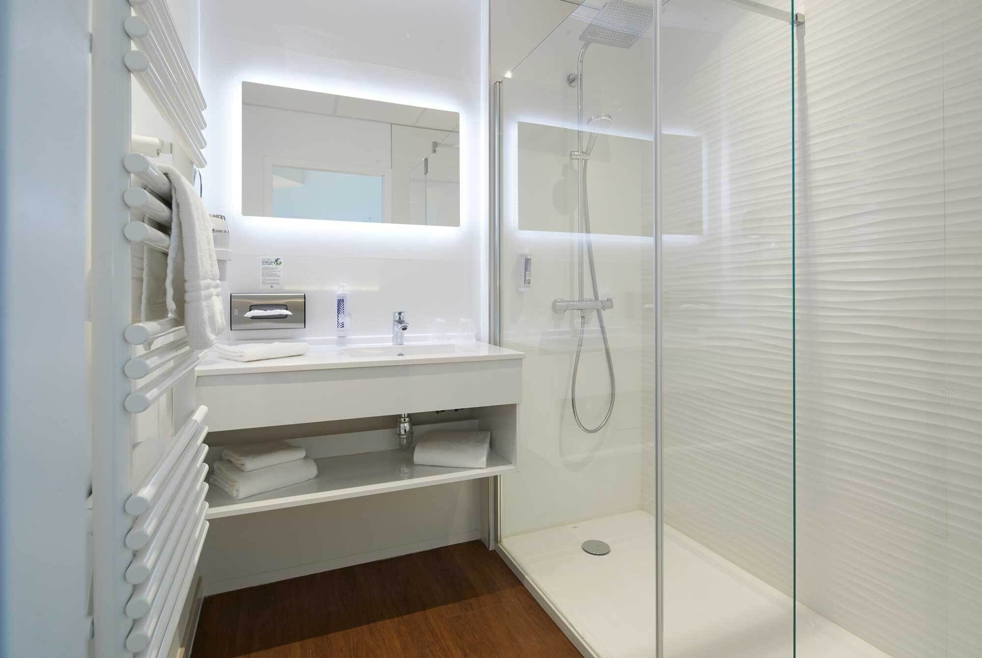 A modern bathroom with a glass shower enclosure, a vanity with a mirror, and a towel rack.