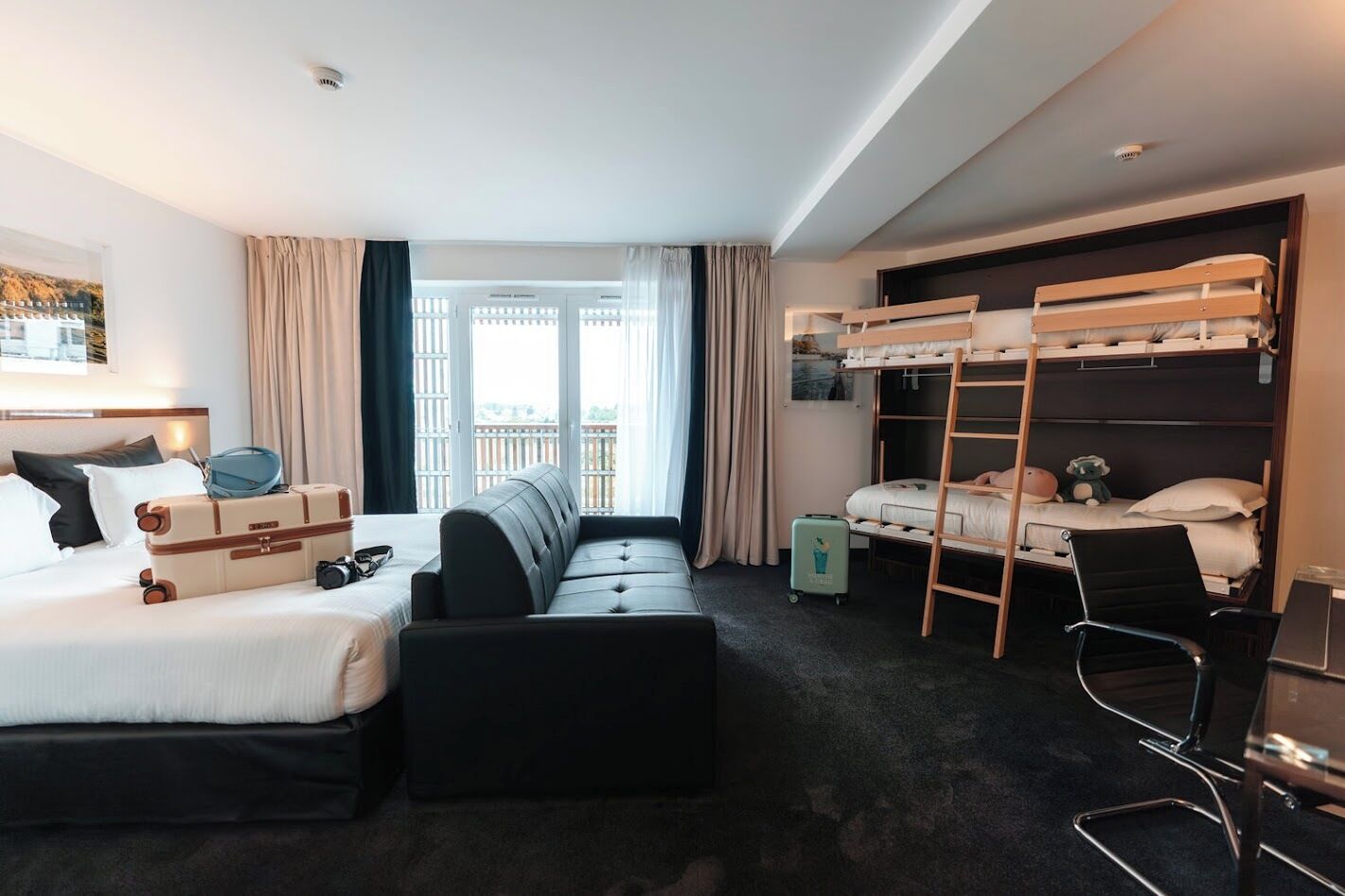 Une chambre d’hôtel comprenant un lit, un canapé, un lit superposé, un bureau et une chaise.
