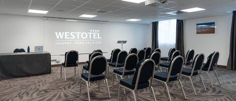 A conference room with a large screen displaying "WESTOTEL TAVERNY - PARIS VAL-D'OISE" at the front.