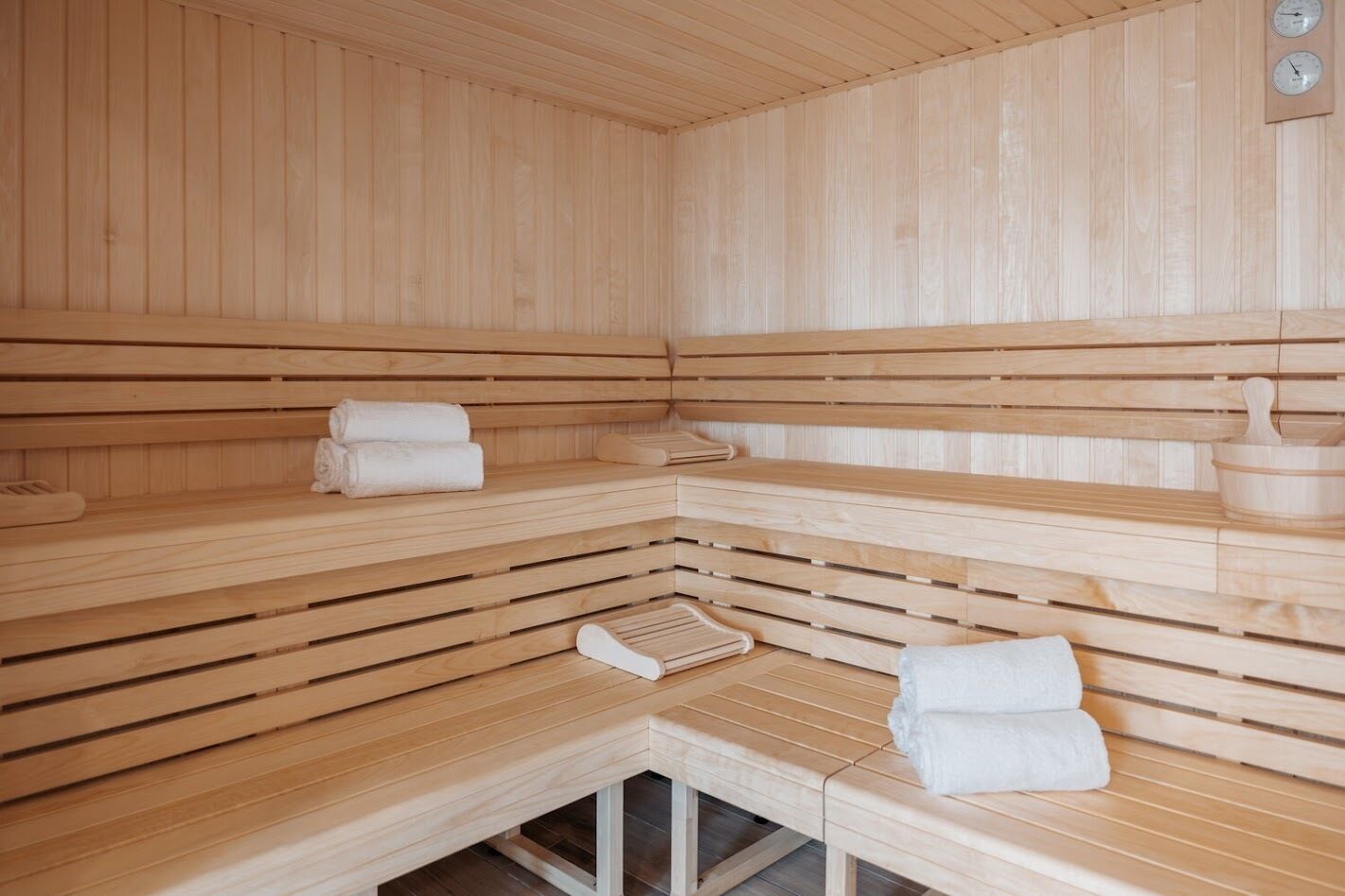 A sauna with wooden benches and benches, towels, and a wooden bench with a bench seat.