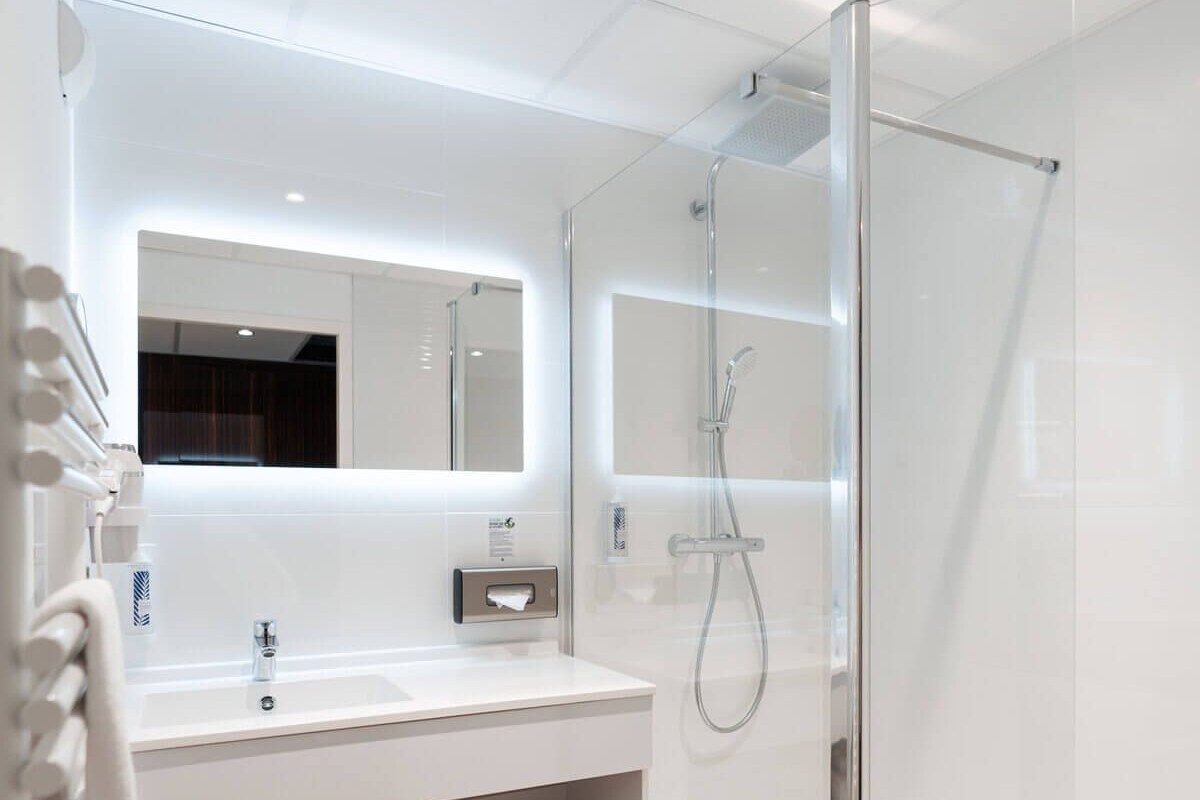 Un bagno moderno con doccia vetrata, un mobile lavabo bianco con specchio e un porta asciugamani.