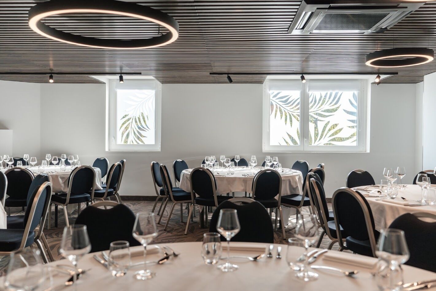 A dining area with round tables, chairs, and overhead lighting.